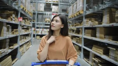 Alışveriş konsepti 4k Çözünürlük. Asyalı bir kadın depoda ürünlere bakıyor..