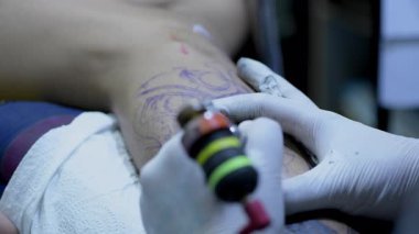 4k Çözünürlük Dövmesi. Sanatçı, Asyalı adamın vücut sanatını yarattı, el ve dövme makinesine yakın plan.