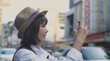 Seyahat konsepti 4k Çözünürlük. Bir kadın cep telefonuyla fotoğraf çekiyor, Çin Mahallesi 'nin canlı şehir manzarasını yakalıyor..