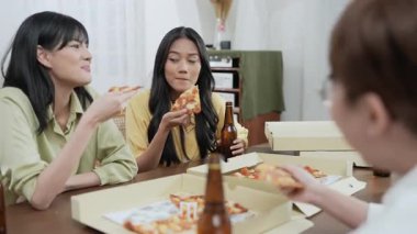 Tatil konsepti 4k Çözünürlük. Bir grup Asyalı bayan arkadaş evde birlikte pizza yiyorlar. Eğlenceli ve heyecan verici eğlence aktiviteleri.