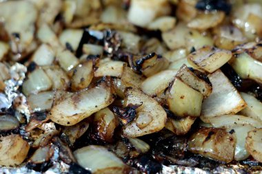 Terbiye edilmiş soğan dilimleri sıcak bahar günlerinde banliyö aile evinin arka bahçesindeki ızgaranın üzerinde lezzetli bir tadı korumak için teneke folyoda ızgara yapıyor.