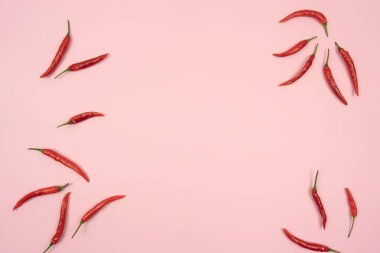 Kırmızı kırmızı kırmızı biber pembe bir arka plan masasında yatar. Uzayı kopyala Metin için çerçeve
