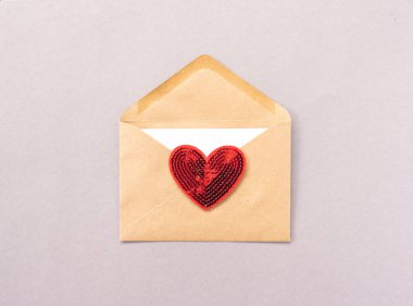 Sevgililer Günü 'nde kırmızı bir kalp kahverengi bir zarfın üzerinde durur.
