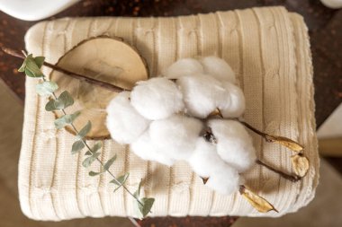 Bir el yapımı sabun ve yeşil bir okaliptüs dalı gri pamuk havluların üzerinde yatıyor.