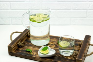 Limonatadan yapılmış ev yapımı bir limonata bardakta duruyor ve tahta bir tepside sürahi.