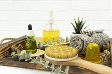 Yüz yağı ve yüz silindiri, kuru masaj için fırça ve tahta tepside bir pamuk havlu.
