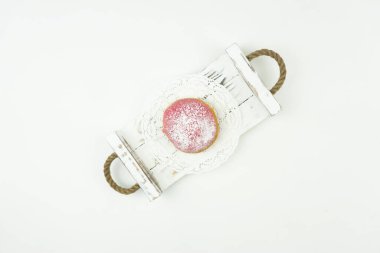 Lezzetli bir donut beyaz bir ahşap tepside yatıyor.