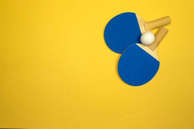 İki masa tenisi raketi renkli bir masa tenisi masasında yarışmalar için hazır bekliyor.