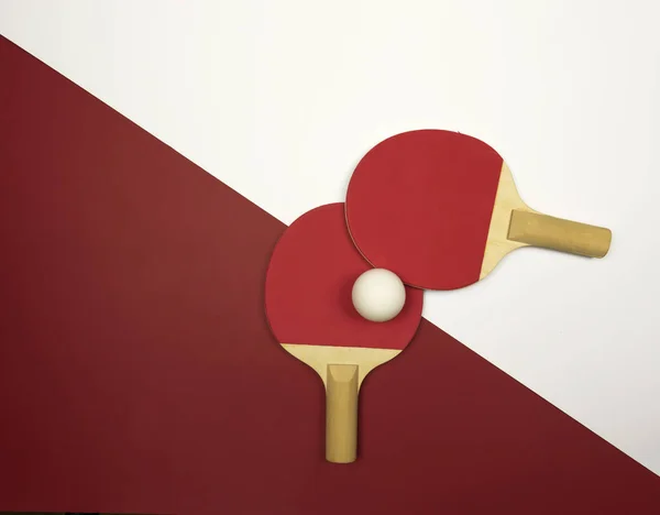 Two table tennis rackets lie on a colorful ping pong table ready for the competitions