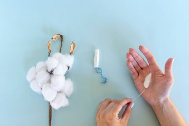 Bir kadın elinde beyaz hijyenik tampon tutuyor. Adet günleri. Hijyen ve vücut bakımı kavramı