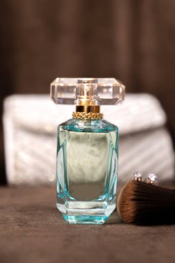 Akşam çantası, makyaj fırçası, küpeler ve parfüm yakın plan.