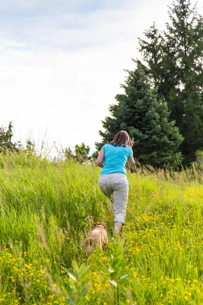 Woman and dog climb hill — Stock Photo, Image