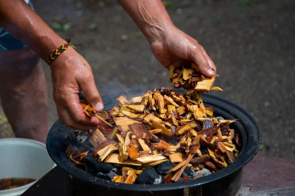 Adding soaked wood chips to the burning charcoal For Smoking Meat On Barbecue. — Stock Photo, Image