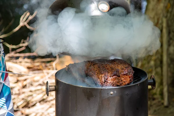 Lever le couvercle pour vérifier une grosse poitrine de bœuf sur un fumeur Photo De Stock