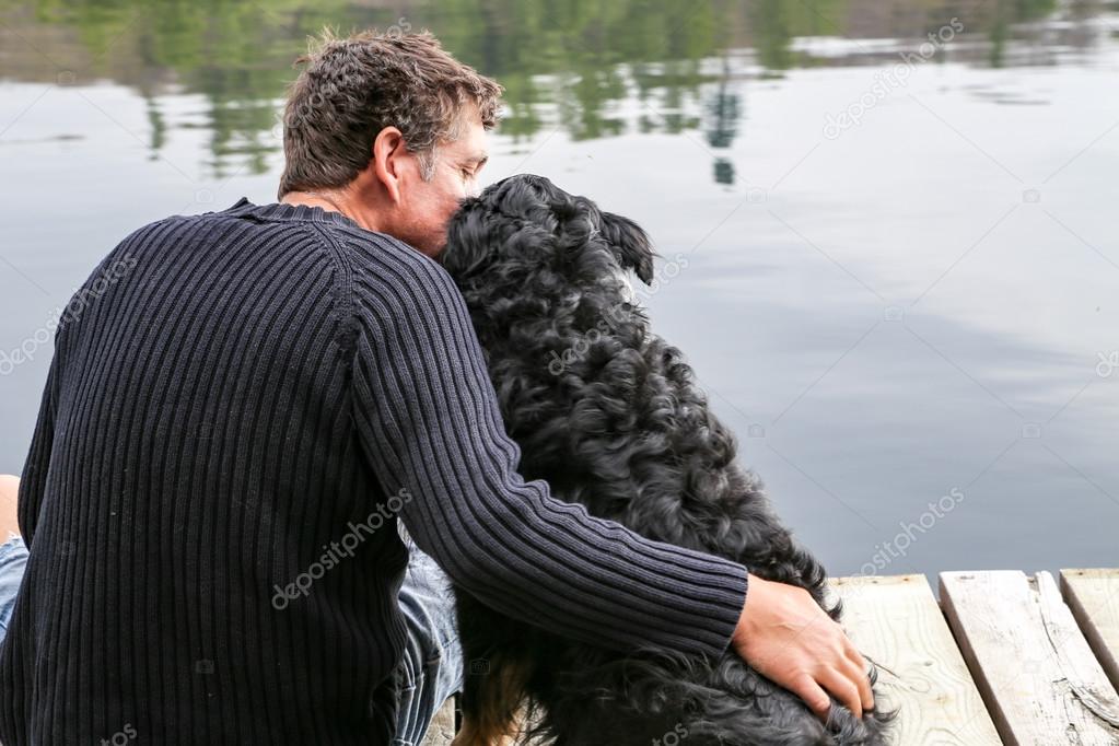 Man snuggles dog at lake