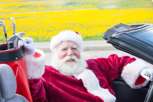 Santa driving convertible with golf clubs — Stock Photo, Image