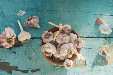 Kırsal ahşap masa üzerinde organik sarımsak karanfilleri ve ampuller, üst görünüm, seçici odak