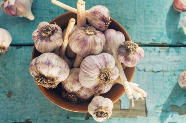 Kırsal ahşap masa üzerinde organik sarımsak karanfilleri ve ampuller, üst görünüm, seçici odak