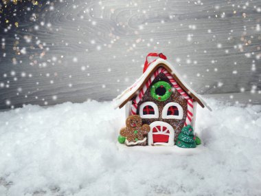 Kar ve çelenk ışıklarıyla süslenmiş kızıl bir Noel evi.