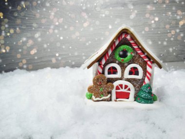 Kar ve çelenk ışıklarıyla süslenmiş kızıl bir Noel evi.