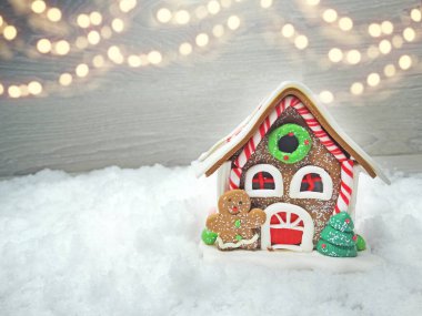 Kar ve çelenk ışıklarıyla süslenmiş kızıl bir Noel evi.