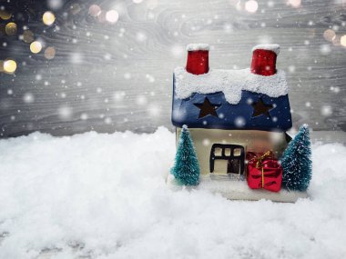 Kar ve çelenk ışıklarıyla süslenmiş kızıl bir Noel evi.