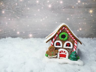 Kar ve çelenk ışıklarıyla süslenmiş kızıl bir Noel evi.