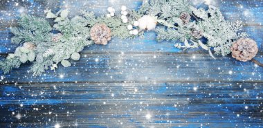 Kış Noel arkaplanı köknar dalları koniler ve mavi ahşap dokuda kar                              