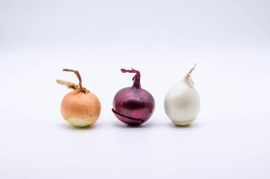 Beyaz arka planda üç farklı renkte soğan. 