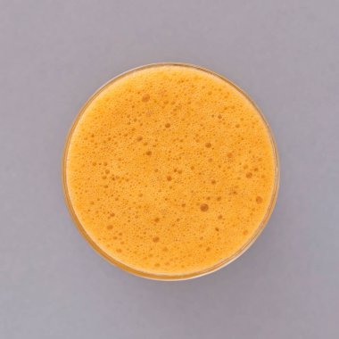 Gri arka planda yuvarlak bir bardakta taze sıkılmış elma suyu.