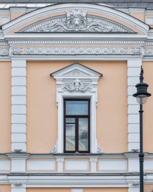 Klasik klasik mimari ön cephe binası. Bir pencere, mimari detaylarla süslenmiş sıva kaplamalı. Ön görünüm.