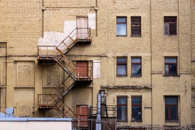Pencereleri ve merdivenleri olan eski sarı tuğla bina cephesi