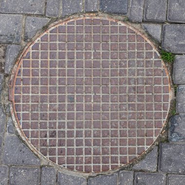 Asfalt manzaralı eski metal rögar kapağı. Kafes deseni