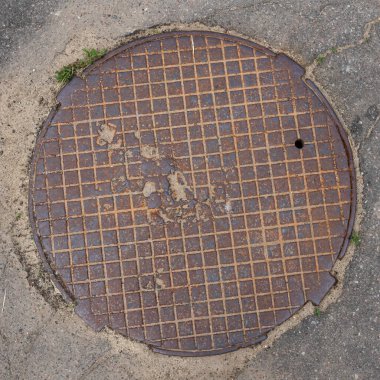 Eski metal paslı rögar kapağı asfalt manzaralı demir kanalizasyon kapağını kapatıyor. Kafes deseni
