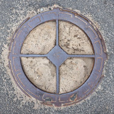 Eski metal paslı rögar kapağı şehrin asfalt manzarasında demir kanalizasyon kapağı. 