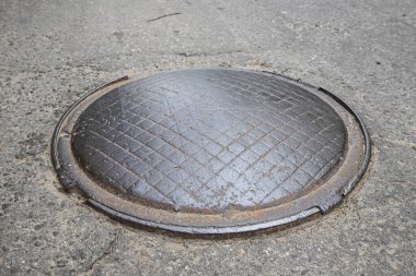 Eski metal dışbükey rögar kapağı bir şehir caddesinde
