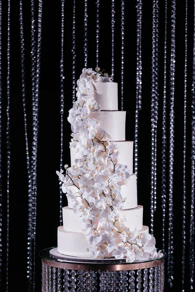 Pastel de boda decorado con orquídeas blancas. Pastel de boda en el fondo brillante. — Foto de Stock