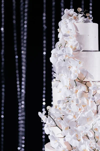 Cerrar pastel de boda decorado con orquídeas. Pastel de boda en el fondo oscuro brillante. — Foto de Stock