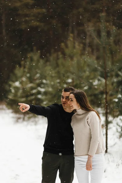 Homem surpreso mostrando à mulher algo na floresta de inverno. Coloque para o seu texto. Amor, relacionamento, férias de inverno. Casal de inverno fotos ideias — Fotografia de Stock