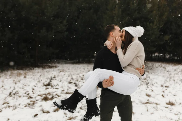 Homem segurando mulher em suas mãos e beijando-a na floresta de inverno. Coloque para o seu texto. Amor, relacionamento, férias de inverno. — Fotografia de Stock