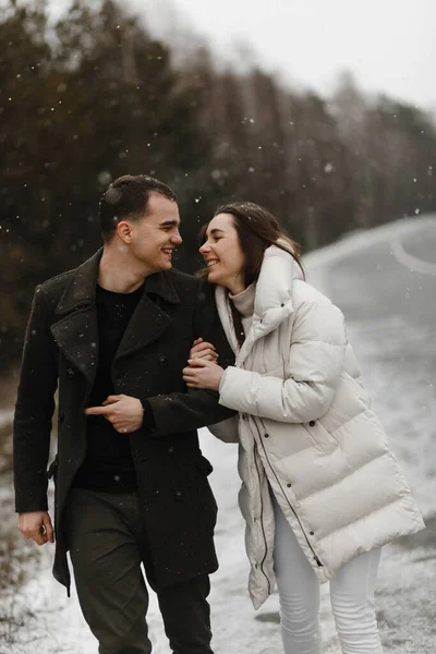 Jóvenes y mujeres que van por el camino de invierno y sonriendo el uno al otro. Amor, relación, vacaciones de invierno. Pareja de invierno fotos ideas —  Fotos de Stock