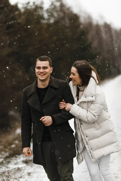 어린 미소짓는 부부가 복제 공간이 있는 겨울 숲의 배경을 비웃고 있습니다. 사랑, 관계, 겨울 휴가. 겨울 부부 사진 아이디어 — 스톡 사진