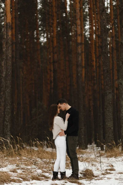 Joven hombre y mujer besándose en el bosque de invierno. Con el lugar para tu mensaje. Amor, relación, vacaciones de invierno. Pareja de invierno fotos ideas —  Fotos de Stock