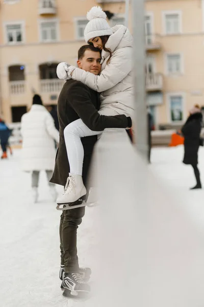 Uomo che abbraccia la donna dopo aver pattinato. Un paio sulla pista di pattinaggio. Divertimento invernale. Storia d'amore — Foto Stock