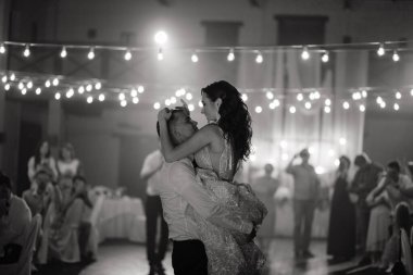 Damat, gülen gelini elinde tutuyor. Düğünde dans eden mutlu yeni evliler. Yeni evliler önce dans eder. Siyah ve beyaz. Yüksek kalite fotoğraf