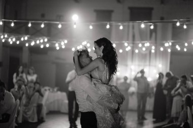 Groom holding the smiling bride in his hands. Happy newlyweds dancing at the wedding party. Newlyweds first dance. Black and white. High quality photo clipart