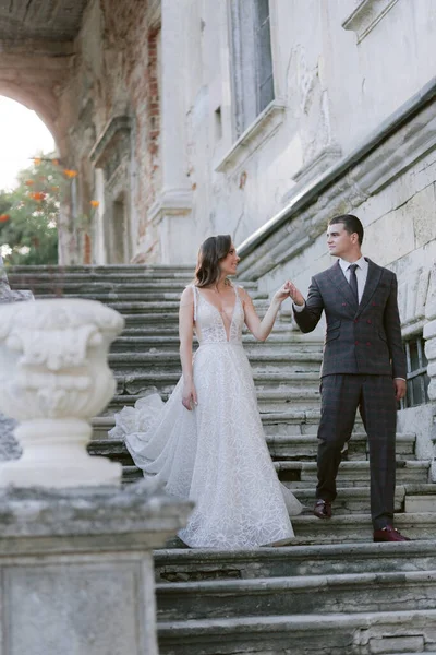 Panna młoda i pan młody schodzą po schodach w starym pałacu i patrzą na siebie. Małżeństwo. Zdjęcie ślubne — Zdjęcie stockowe