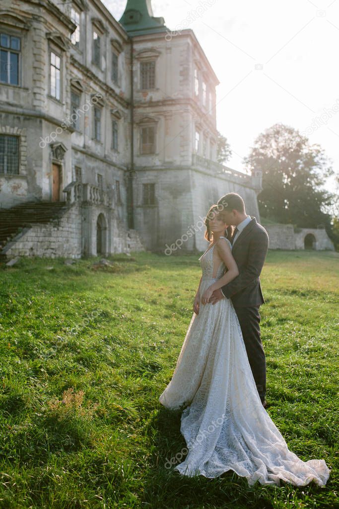Beautiful bride and groom standing in front of old castle. Wedding couple. Wedding photo