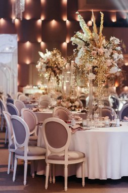 Çiçekler ve mumlarla süslenmiş düğün masasının manzarası. Düğünde misafirler için bir yer. Düğün masası ayarı. Düğün ziyafeti