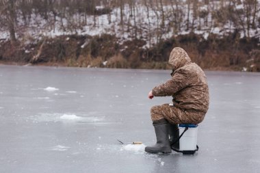 Balıkçı donmuş göldeki buz deliğinde balık yakalıyor. Kışın balık tutan adam. Kış balıkçılığı. Mesajın için yer aç. Yüksek kalite fotoğraf